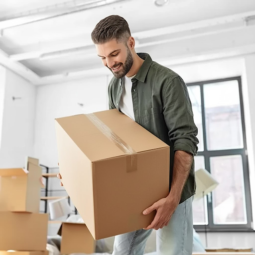 Man carrying a cardboard box in a bright room during moving and storage process at a self storage facility in Gold Coast.